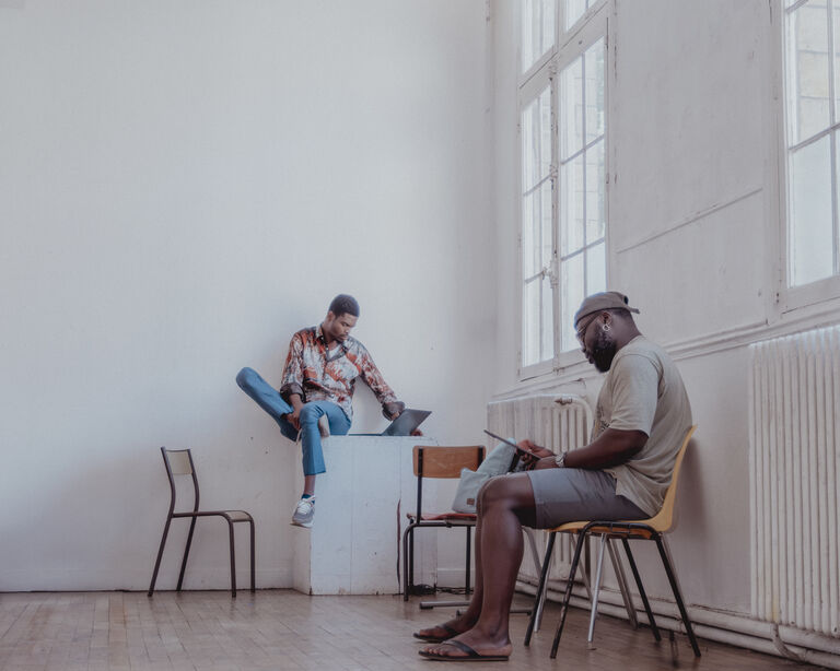 Salle 9 du Labo Victor Hugo. Deux artistes travaillent sur leurs ordinateurs dans une grande salle lumineuse du Labo Victor Hugo, aménagée pour l’accueil de résidences et de projets créatifs.