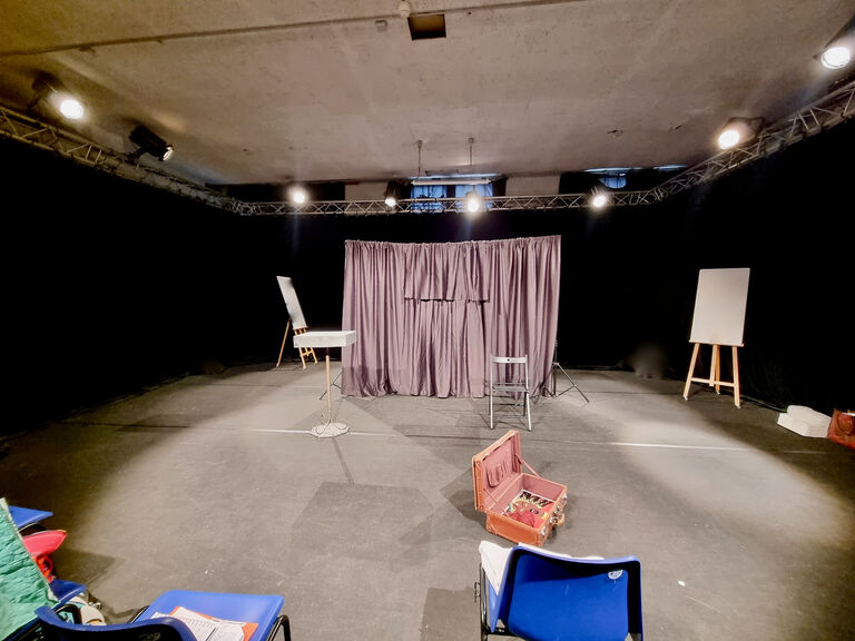 Salle 3 du Labo Victor Hugo aménagée comme une petite scène, avec rideaux, éclairages suspendus, chevalets et espace dégagé pour répétitions ou performances.