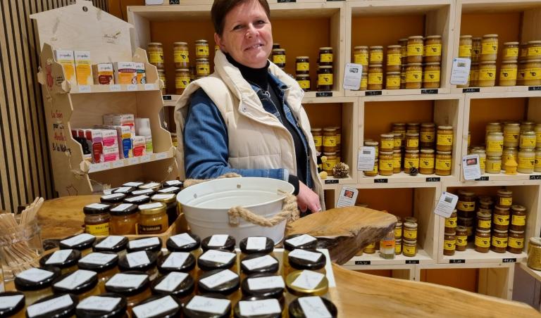 Dorothée entourée de nombreux pots de miel dans sa boutique